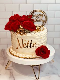 a white cake with red roses on top and the words nette written on it