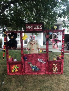 a man dressed as a clown standing in front of a prize booth with stuffed animals