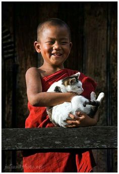 a little boy holding a cat in his arms with a quote on the back ground