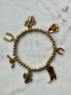 Western-themed Elastic Charm Bracelet featuring your favorite Western accessories! Adjustable Novelty Charm Bracelet, Adjustable Novelty Charms Bracelets, Gold Novelty Bracelets With Charms, Personalized Gold Novelty Bracelets, Adjustable Gold Themed Charm Bracelet, Gold Themed Adjustable Charm Bracelet, Novelty Adjustable Charm Bracelet, Gold Adjustable Novelty Charm Bracelet, Casual Gold Charm Bracelet As Gift