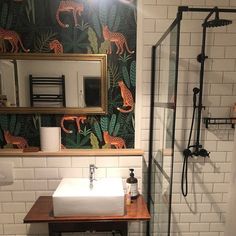 a bathroom with a sink, mirror and shower in it's stall area next to a tiled wall