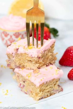 two pieces of cake with frosting and strawberries on the side are being held up by a fork