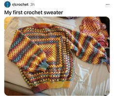 two crocheted sweaters sitting on top of a bed next to each other