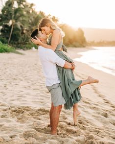 a man carrying a woman on his back while standing in the sand at the beach