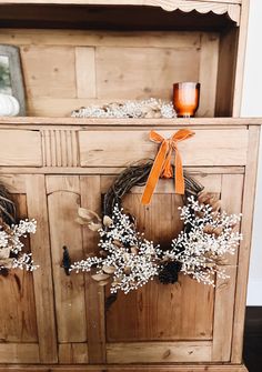 a wooden cabinet with two wreaths on it