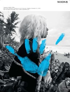 a woman standing on top of a beach next to the ocean with her hands painted blue