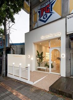 the front entrance of a store with white walls and wooden steps leading up to it