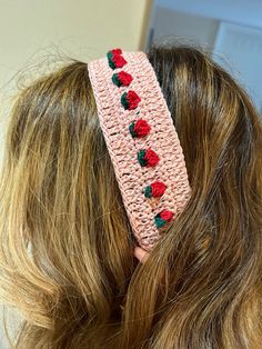 a woman wearing a pink crochet headband with red roses on it's side