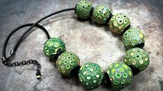 a green and white beaded necklace on a black cord