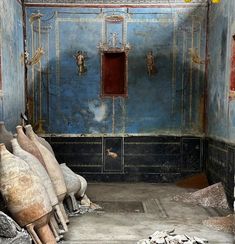 an old room with blue walls and some statues on the floor in front of it