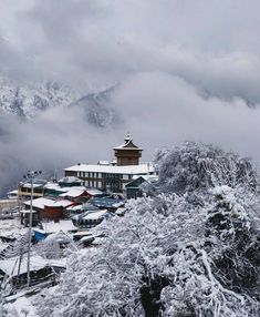 snow covered mountains and houses in the foreground, with low lying clouds behind them