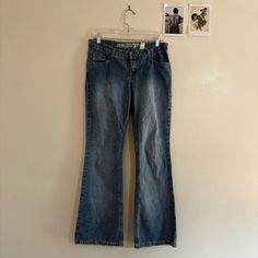 Rugged, worn light wash jeans with a gorgeous bell bottom cut -almost a puddle style. Solid pair of vintage jeans that feel very 2000s-does-70s. Low waisted with a fairly long inseam. Brand on tag: "Mudd." Mudd is a well-known, iconic American brand whose older items are incredibly sought after. High quality denim with a fun, trendy, youthful twist has always been their bread and butter. Tag size reads: 9. There is fraying around the bottom hems, but this is intentional distressing. 100% cotton. Measurements (Flay Lay): Waist 16", Front rise 8.5", Hips 18", Inseam 31.5", Leg opening 9.5" No damage was detected on the piece. NO RETURNS (Unless damage is discovered by the buyer on a piece that was not disclosed/photographed by me.) Y2k Style Medium Wash Wide Leg Flare Jeans, Y2k Style Flare Jeans For Spring, Y2k Style Medium Wash Spring Flare Jeans, 90s Style Medium Wash Wide Leg Flare Jeans, Light Wash Mid-rise Y2k Jeans, 90s Style Mid-rise Medium Wash Flare Jeans, 90s Style Medium Wash Denim Flare Jeans, 90s Style Medium Wash Flare Denim Jeans, Y2k Flare Jeans