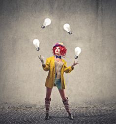 a woman with red hair is juggling light bulbs