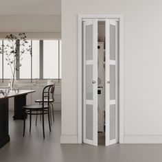 an open door in the middle of a kitchen with chairs and table next to it