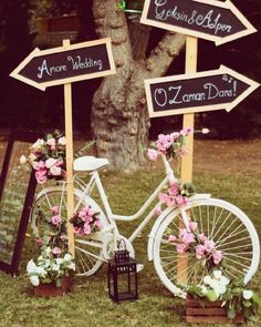 a white bicycle with flowers on it parked in front of a sign that says wedding