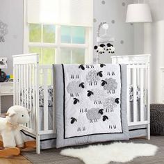 a baby crib with sheep on it and a teddy bear next to the crib