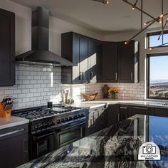 a kitchen with marble counter tops and stainless steel appliances, along with dark wood cabinets