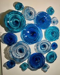 blue and white glass flowers are arranged in a circular pattern on a white table top