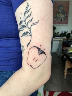 a woman's arm with an apple tattoo on the left side of her arm