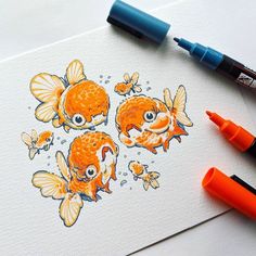 two goldfishs are drawn on paper with marker pens and markers next to them