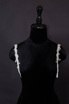 a black mannequin with white ruffles on it's back and sides