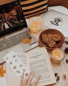 a laptop computer sitting on top of a table next to a cup of coffee and cookies