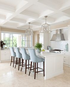 a kitchen filled with lots of white counter tops and blue bar stools next to a stove top oven