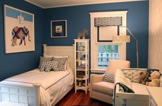 a bedroom with blue walls and white furniture, including a small child's bed