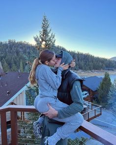 a man and woman kissing while standing on a balcony