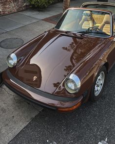 a brown sports car is parked on the street