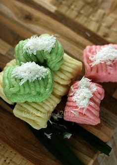 three different colored cookies sitting on top of a wooden cutting board