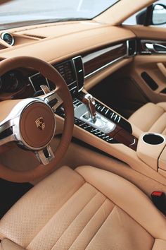 the interior of a luxury car with beige leather and wood trims, steering wheel and center console