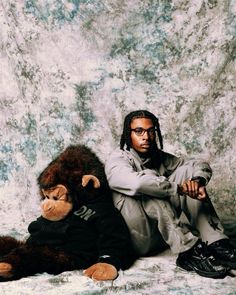 a man sitting on the ground next to a stuffed monkey