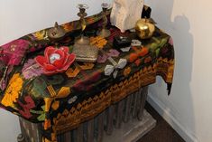 a table covered with decorative items next to a radiator in a white walled room