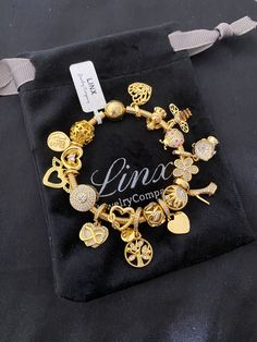 Linx snake chain style charm bracelet in 925 sterling silver, with a ball clasp. Bracelet is available in multiple sizes.  *Bracelet will arrive in a luxury velvet jewelry pouch, making it perfect for gift giving also.  *Bracelet comes with 18 Linx charms in 14k yellow gold over 925 sterling silver. Includes paved heart safety clip charm. * Additional charms can also be added to this bracelet.  *Bracelet is compatible with all standard size charms, so you can add all of your favorite Pandora cha Cubic Zirconia Charm Bracelet Gift, Luxury Jewelry With Dangling Charms, Luxury Jewelry With Dangling Charms For Gifts, Elegant Snake Chain Charm Bracelet For Gift, Luxury Dangling Charms Jewelry For Gifts, Luxury Dangling Charms Jewelry Gift, Luxury Removable Charms For Gifts, Luxury Charm Bracelet - Perfect Gift, Luxury Jewelry With Charms On Snake Chain