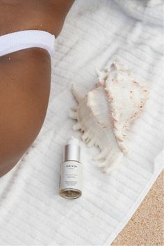 a woman laying on top of a towel next to a bottle of sunscreenr