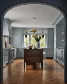 an archway leads into a kitchen with blue cabinets and wood floors, along with a center island in the middle