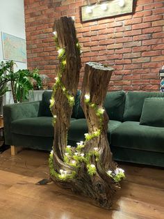 two tree stumps with lights on them in front of a green couch and brick wall