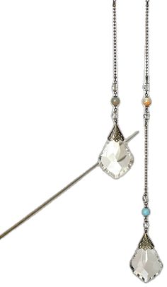 a pair of earrings hanging from a long silver chain with crystal stones on the end