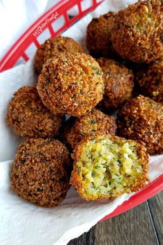 a red basket filled with meatballs on top of a white paper towel next to a wooden table