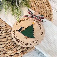 a wooden ornament with a christmas tree on it sitting next to a basket