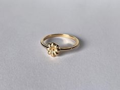 a gold ring with a four leaf clover on the front and center, sitting on a white surface