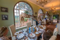 a giraffe is eating at a restaurant with people sitting around the table watching