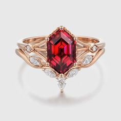 a red stone ring with white diamonds on the sides and an oval cut diamond in the middle