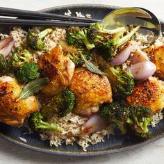 a blue plate topped with chicken and broccoli covered in rice next to chopsticks