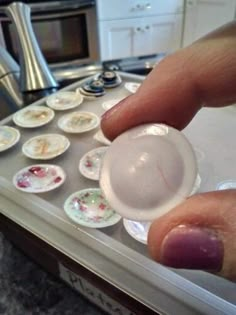 a person holding a plastic object in their hand near some plates on the kitchen counter