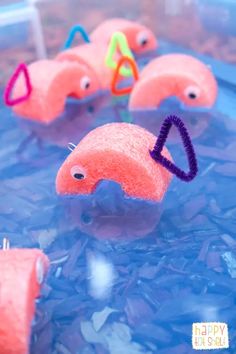 some pink toys are sitting in the water and one is holding a purple object with two eyes