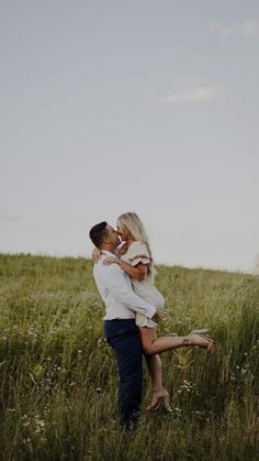 a man and woman kissing in the middle of a field