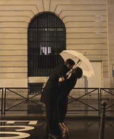 two people kissing under an umbrella in front of a building with black iron bars on it