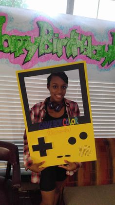 a woman holding up a video game controller cardboard sign with the words happy birthday on it